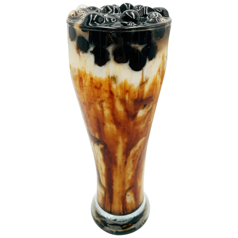 Verre de thé au lait noir avec perles de tapioca et coulis de caramel sur fond blanc