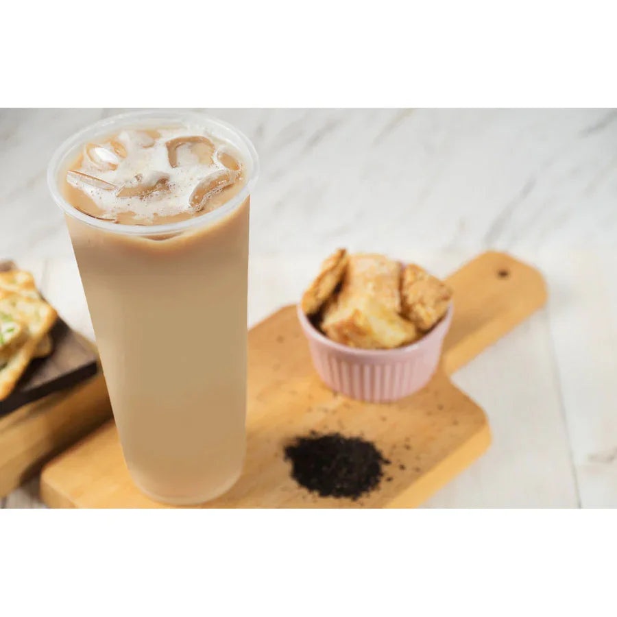 Boisson bubble tea glacée dans un gobelet transparent, servie sur planche en bois avec thé en feuilles et biscuits