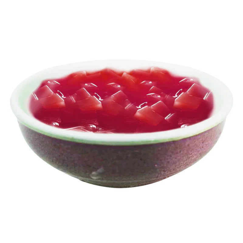 Bol en céramique rempli de gelée rouge avec morceaux de fruits en cubes