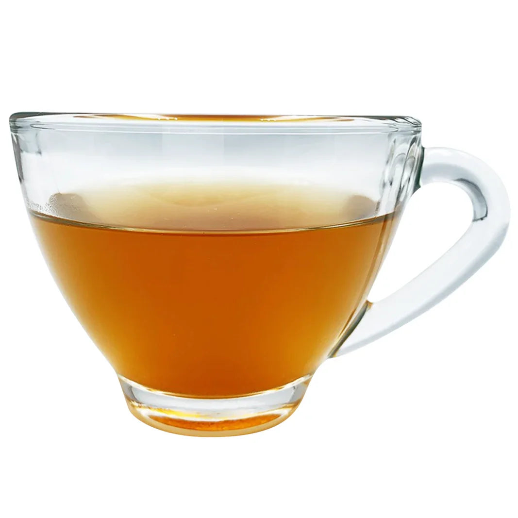 Tasse en verre transparent remplie de thé brun clair sur fond blanc