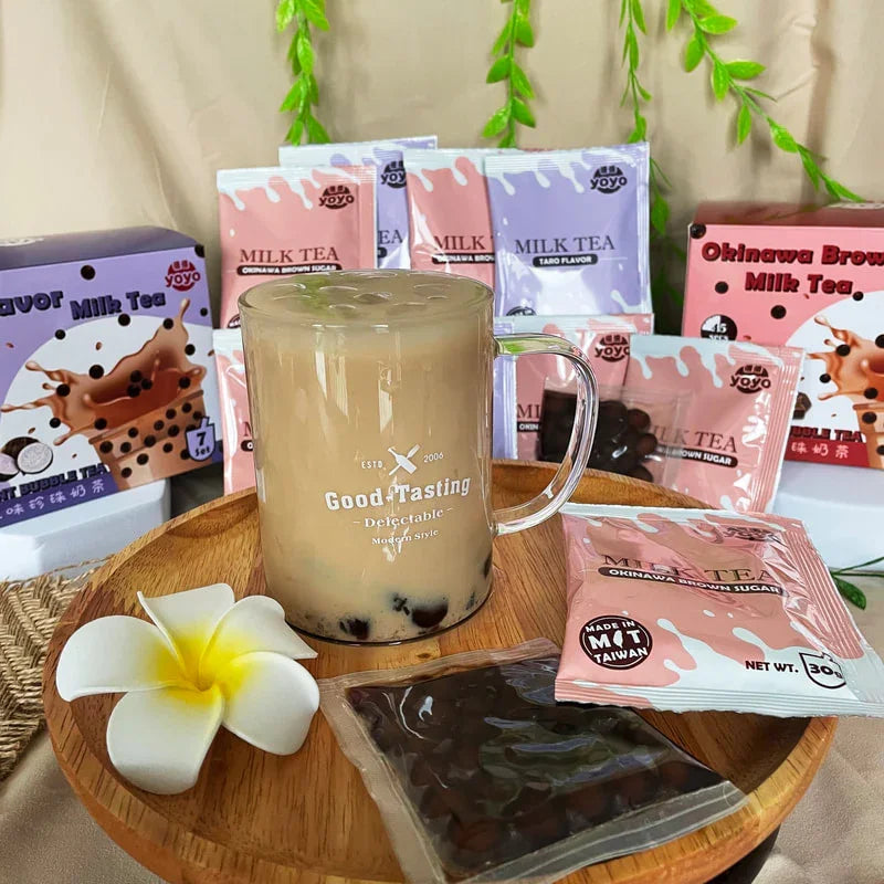 Verre de thé au lait avec perles de tapioca sur plateau en bois, sachets de thé au sucre brun Okinawa en arrière-plan