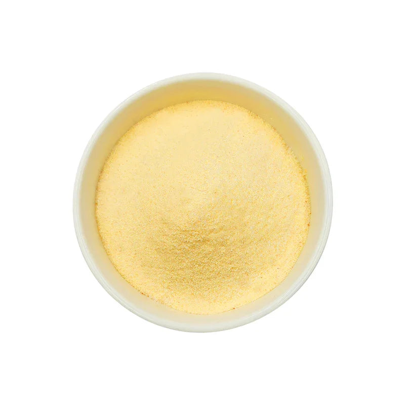 Poudre fine jaune clair dans un bol blanc sur fond blanc, poudre alimentaire ananas