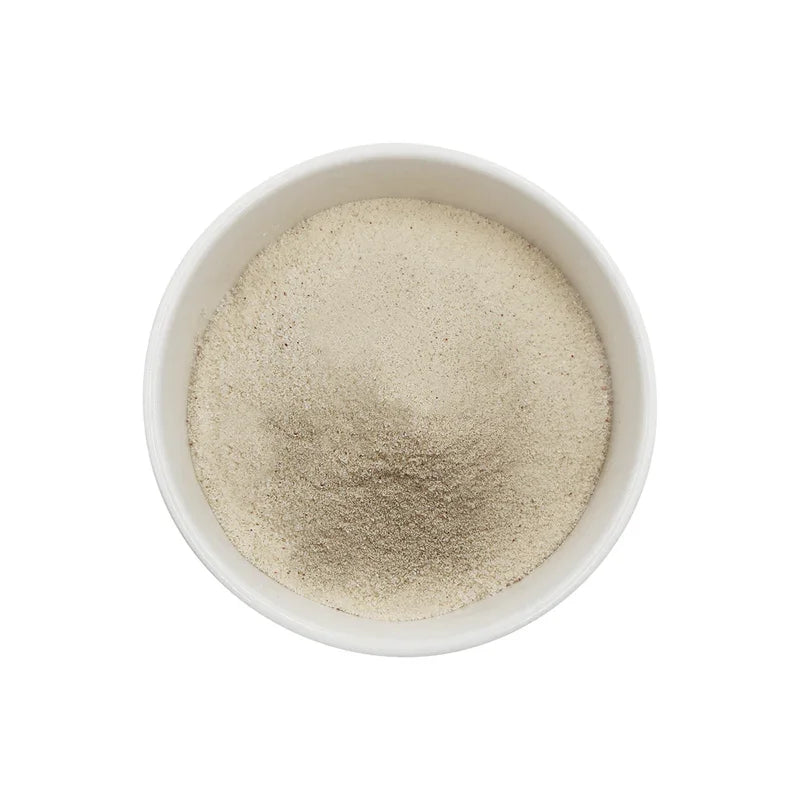 Poudre caramel blanc fine dans un bol blanc sur fond blanc, texture douce et poudreuse