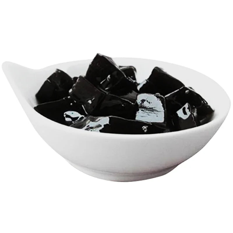 Bol blanc contenant des cubes de gelée noire brillante, dessert asiatique populaire
