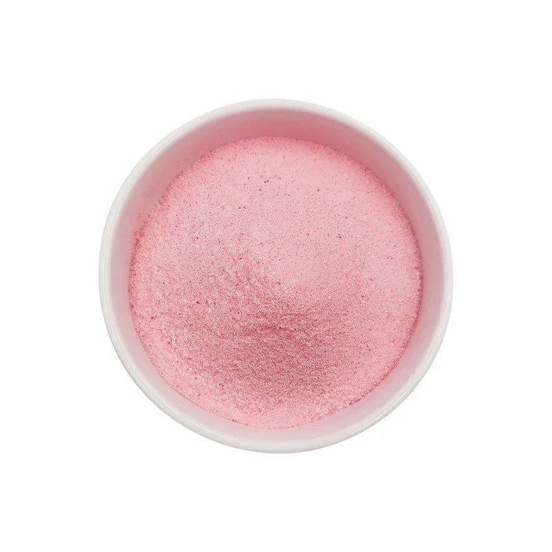 Poudre fine rose de goyave dans un bol blanc sur fond blanc, texture lisse et uniforme