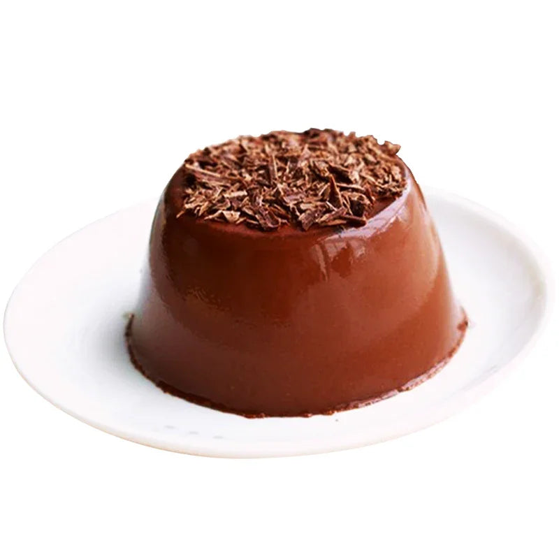 Pudding au chocolat lisse avec copeaux de chocolat sur le dessus, servi sur assiette blanche