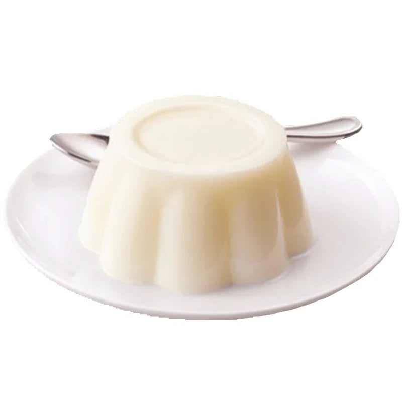 Pudding au lait blanc servi sur une assiette blanche avec une cuillère en métal