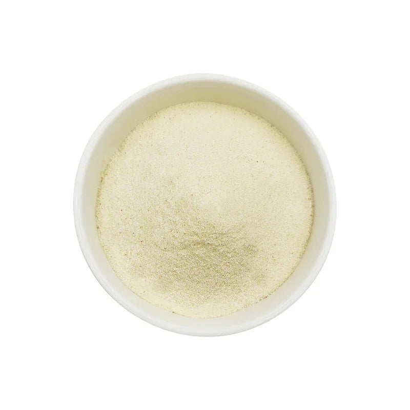 Poudre fine beige clair dans un bol blanc sur fond blanc, poudre au lait banane