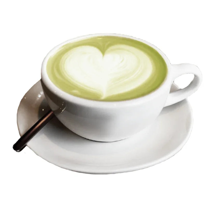 Tasse blanche de thé au lait matcha avec art latte cœur sur une soucoupe blanche et cuillère