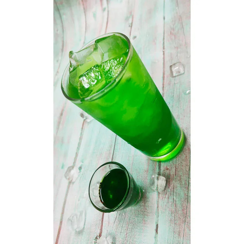 Verre élevé et petit verre de sirop vert kiwi sur table en bois avec glaçons
