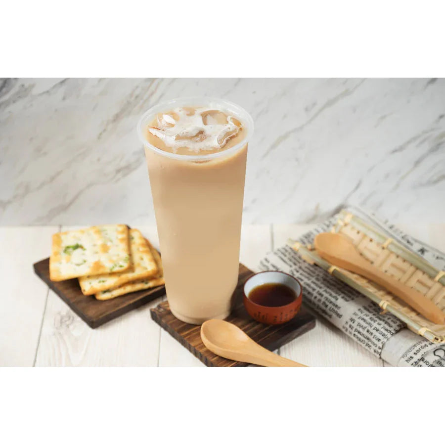 Boisson glacée lactée avec glaçons, crackers sur plateau, petit bol de sauce et cuillère en bois sur table claire