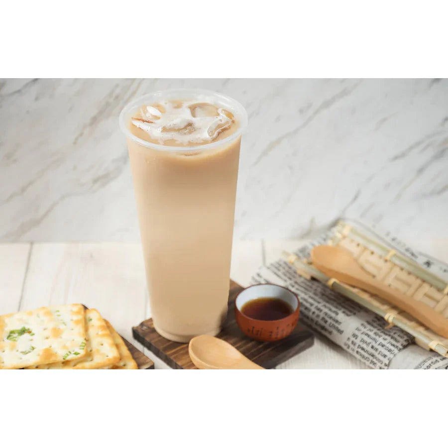 Boisson glacée au lait avec glaçons sur table en bois, accompagnée de biscuits salés et petit bol