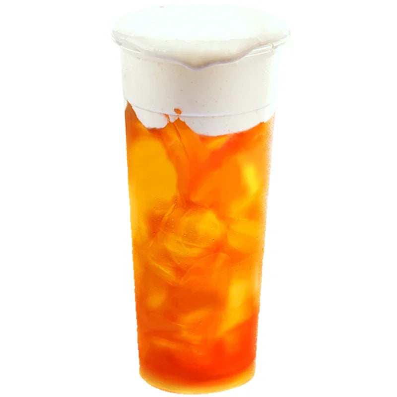 Boisson glacée orange avec mousse blanche au fromage sur le dessus, verre translucide avec glaçons