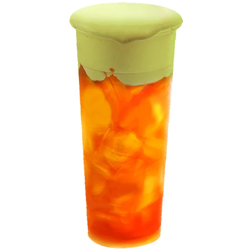 Boisson froide orange avec mousse épaisse verte au matcha sur le dessus, verre transparent