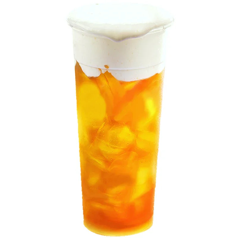 Verre de thé glacé orange avec glace et mousse de lait blanc onctueuse sur le dessus