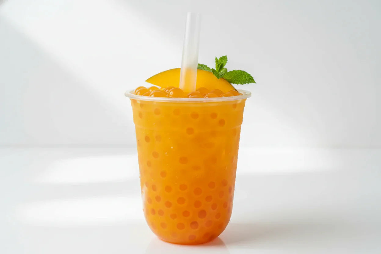 Bubble tea mangue avec perles de fruit orange, tranche de mangue et feuille de menthe